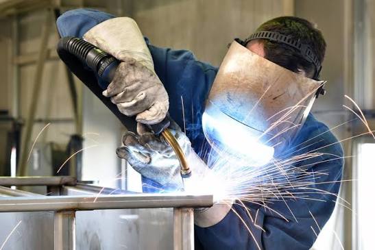 Welder using a welding torch to weld metal